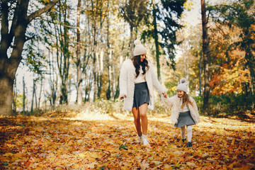 Fototapeta premium Beautiful mother with daughter. Family in a autumn park. Golden autumn