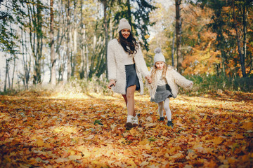 Naklejka na ściany i meble Beautiful mother with daughter. Family in a autumn park. Golden autumn