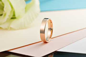 Gold ring on colored background with flower