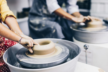 Happy mother and daughter making clay pottery on a spin wheel. .