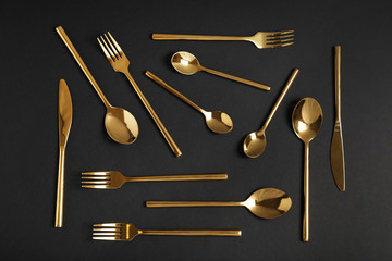 Flat lay composition with gold cutlery on black background