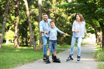 Young happy family roller skating in summer park