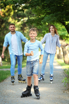 Young happy family roller skating in summer park