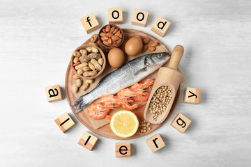 Flat lay composition of different products and wooden cubes with words FOOD ALLERGY on white table