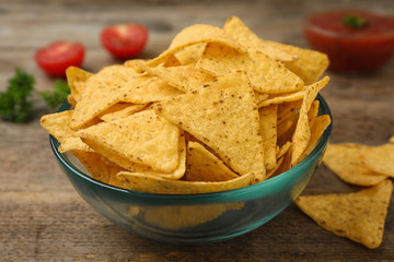 Bowl of Mexican nacho chips on wooden table, closeup