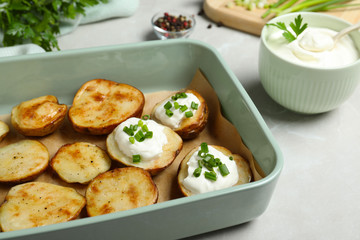 Sour cream and delicious potato wedges on light grey table