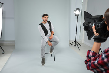 Professional photographer taking picture of young man in modern studio