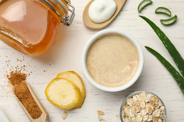 Different ingredients and handmade face mask on white wooden background, flat lay