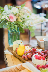cheese platter with pear, grapes, berries, blue cheese, brie, crackers, on a wooden cutting board, fancy cheese plate at wedding, event appetizers 
