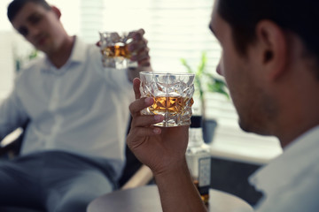 Young men drinking whiskey together at home