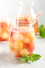 Glasses of melon and watermelon ball cocktail with mint on light marble table