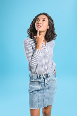 Thoughtful young woman in casual outfit on blue background