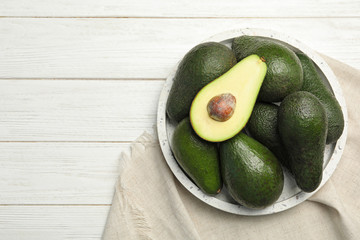 Delicious ripe avocados om white wooden table, top view. Space for text
