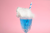 Cocktail with cotton candy in glass on pink background, closeup view