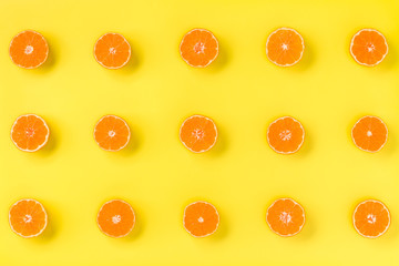 Fruit pattern of fresh mandarin slices on yellow background. Flat lay, top view. Pop art design, creative summer concept. Half of citrus in minimal style. Tangerine.