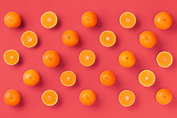 Fruit pattern of fresh orange tangerine or mandarin on living coral background. Flat lay, top view. Pop art design, creative summer concept. Citrus in minimal style.
