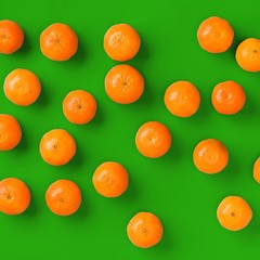 Fruit pattern of fresh orange tangerine or mandarin on green background. Flat lay, top view. Pop art design, creative summer concept. Citrus in minimal style.