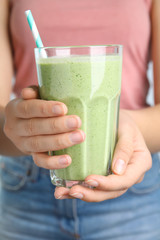 Young woman holding glass of tasty avocado smoothie with straw, closeup