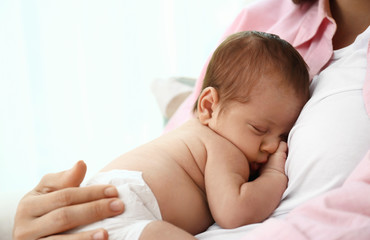 Young mother with her little baby on light background