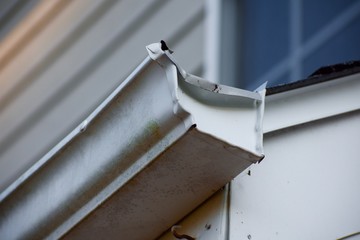 Mangled gutter on the side of a tan house