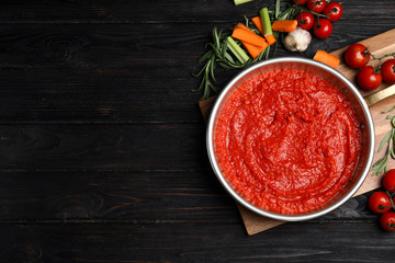 Flat lay composition with delicious tomato sauce on black wooden table. Space for text
