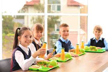 Happy children at table with healthy food in school canteen