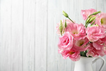 Eustoma flowers in vase near white wall, space for text
