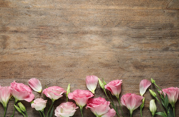 Flat lay composition with beautiful Eustoma flowers on wooden table, space for text