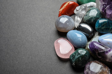 Flat lay composition with different gemstones on dark table, space for text