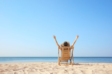 Young woman relaxing in deck chair on sandy beach