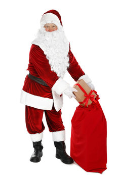 Authentic Santa Claus with sack and gifts on white background