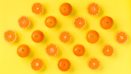 Fruit pattern of fresh mandarin slices on yellow background. Flat lay, top view. Pop art design, creative summer concept. Half of citrus in minimal style. Tangerine.