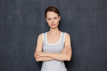 Fototapeta na wymiar Portrait of calm young woman holding arms crossed on chest