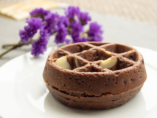 chocolate waffle with almond slide on a white plate, purple flower, fresh baked for sweet meal, dessert concept.