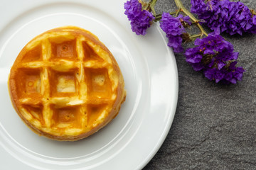 vanilla waffle on a white plate with purple flower, fresh baked for sweet meal, dessert concept.