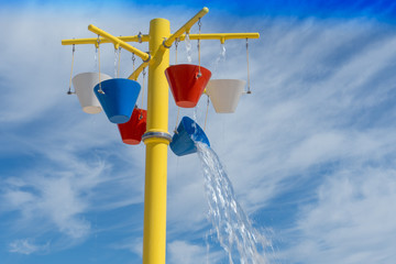 Assorted colorful buckets of water pouring on a splashpad in the summer