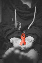 child with AID red ribbon on a dark background.black and white.
