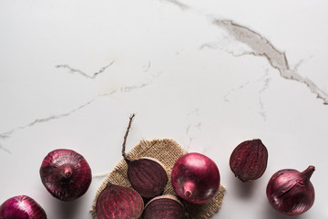 top view of beetroots and red onions on marble surface with hessian