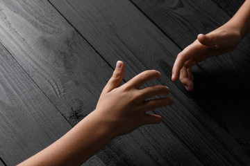 arms stretches out and holds one another on a black wooden background