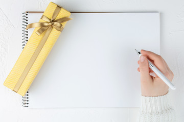 hands hold an blank notebook among gift box. Flat lay.