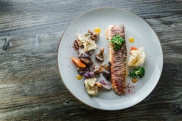 top view on exclusive decorated baked fish fillet and vegetables