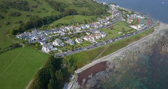 Aerial footage flying over Cornish sea, coastline and houses at Looe, Cornwall, UK