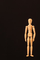 standing wooden mannequin black background