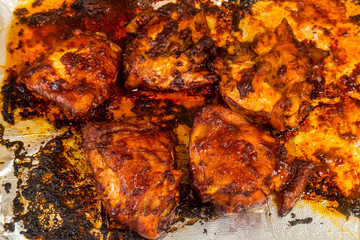 Adobo Chicken Thighs on Baking Sheet covered in Barbecue Sauce and Spicy Seasonings