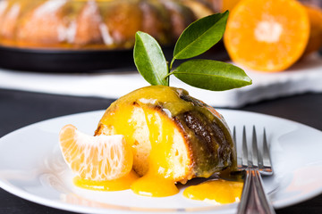Pedaço de bolo de tangerina delicioso com calda cremosa no prato branco sobre mesa de madeira cor...