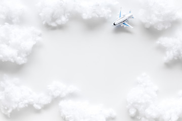 Fly by plane concept. Airplane model and clouds on white background top view frame copy space