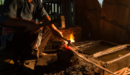 Professional Blacksmith at work is Hit the iron by a hot metal With fire