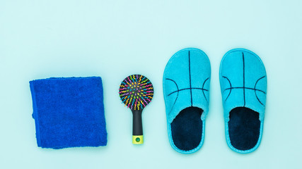 Blue Slippers, towel and comb on blue background.