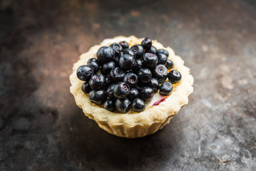 Bilberry cake decorated with fresh ripe berries on the rustic background. Selective focus. Shallow depth of field. 