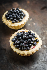 Bilberry cake decorated with fresh ripe berries on the rustic background. Selective focus. Shallow depth of field. 